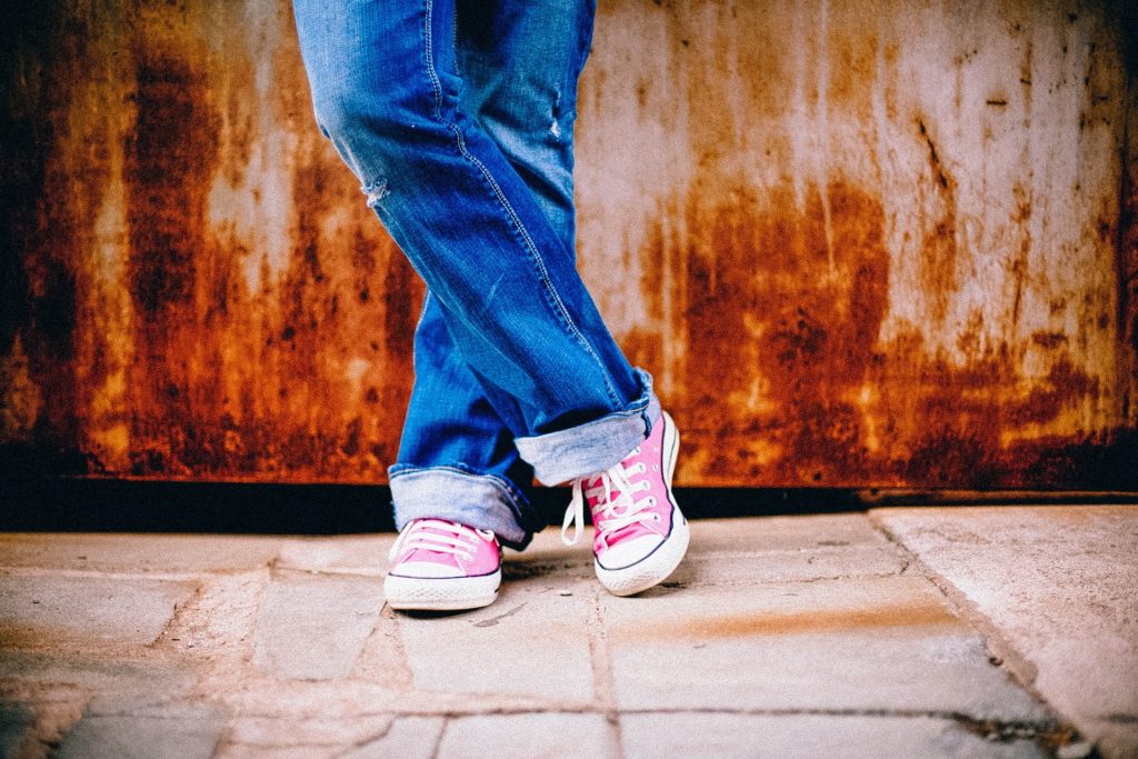 A person wearing blue jeans and pink shoes